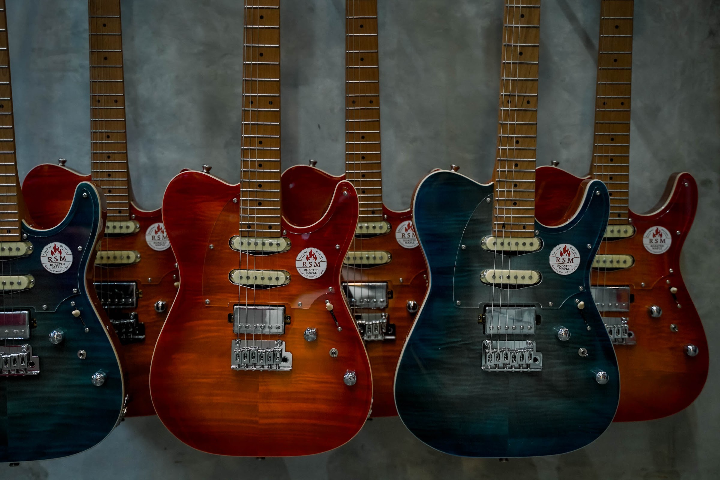 Deretan gitar Bacchus warna biru dan merah sunburst tergantung di dinding REMIX