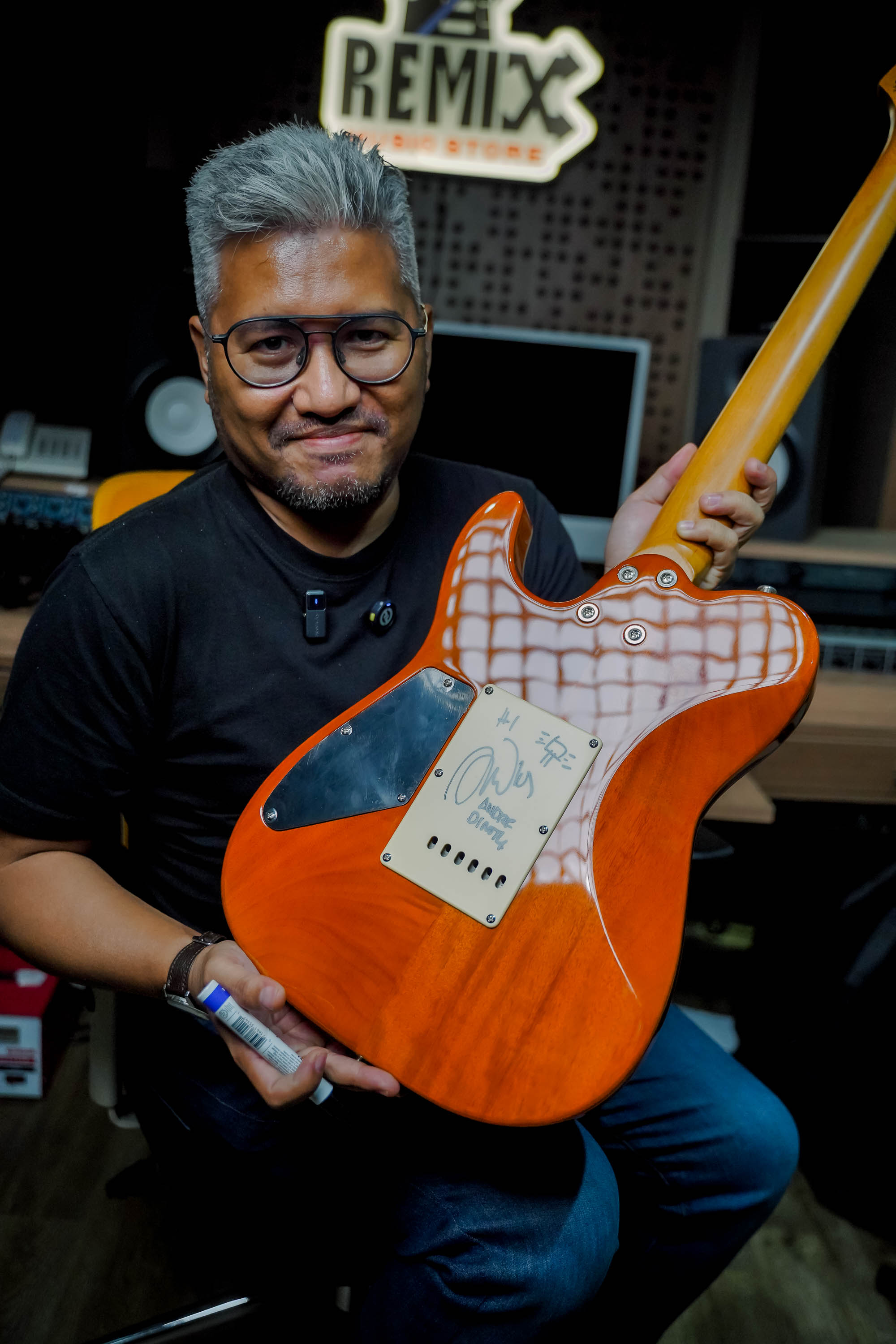 Andre Dinuth tersenyum sambil memegang salah satu gitar bernomor yang baru ia tanda tangani